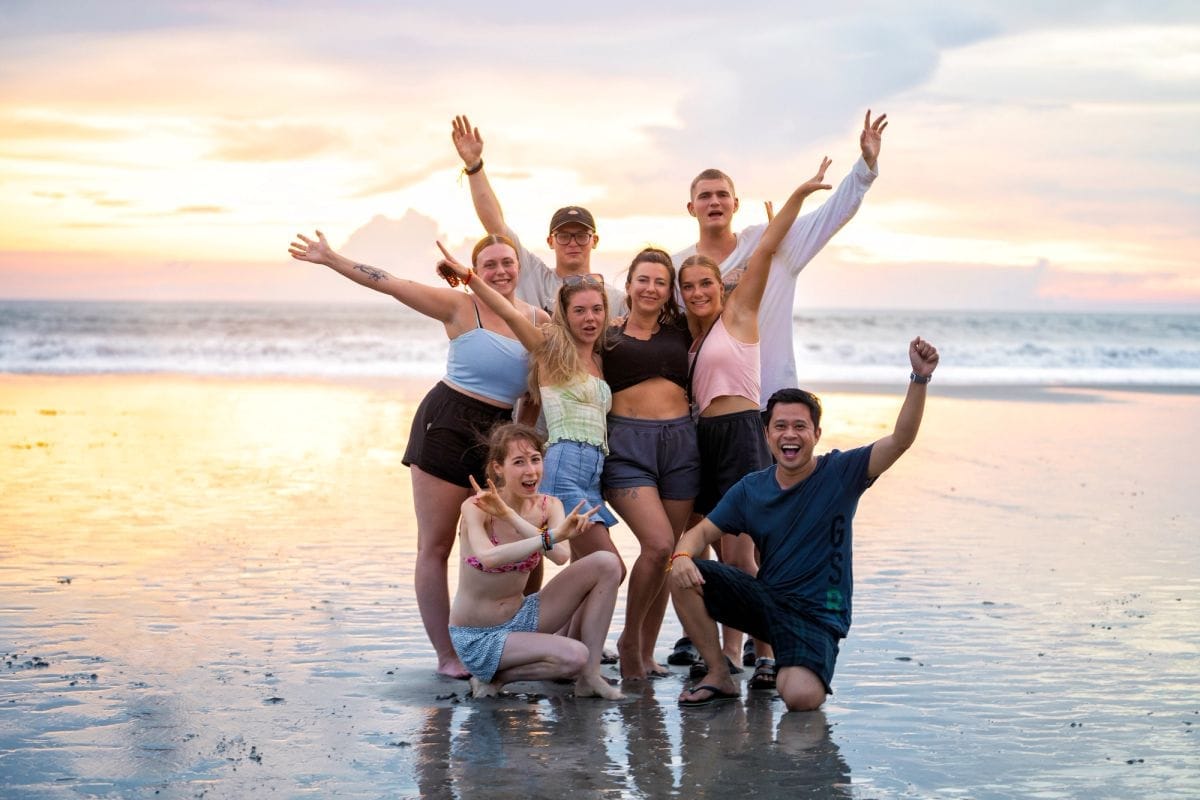 A Bali tour group celebrating on the beach at sunset