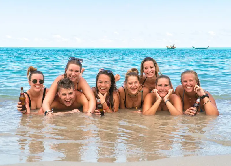 A big group of Wanderlust travellers laughing together in the sea in Thailand