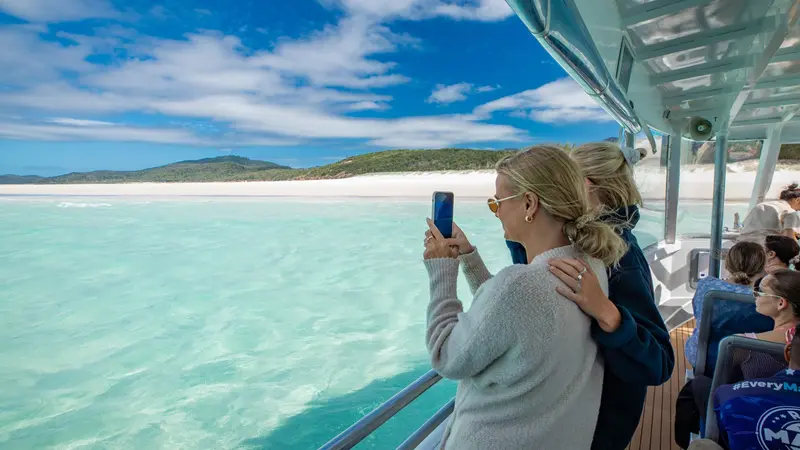 Two friends photographing Whitehaven Beach from the boat deck in the Whitsundays