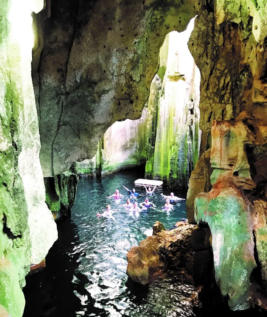 Swimmers in the limestone cave pool at Sawa-i-Lau, lit from an opening above