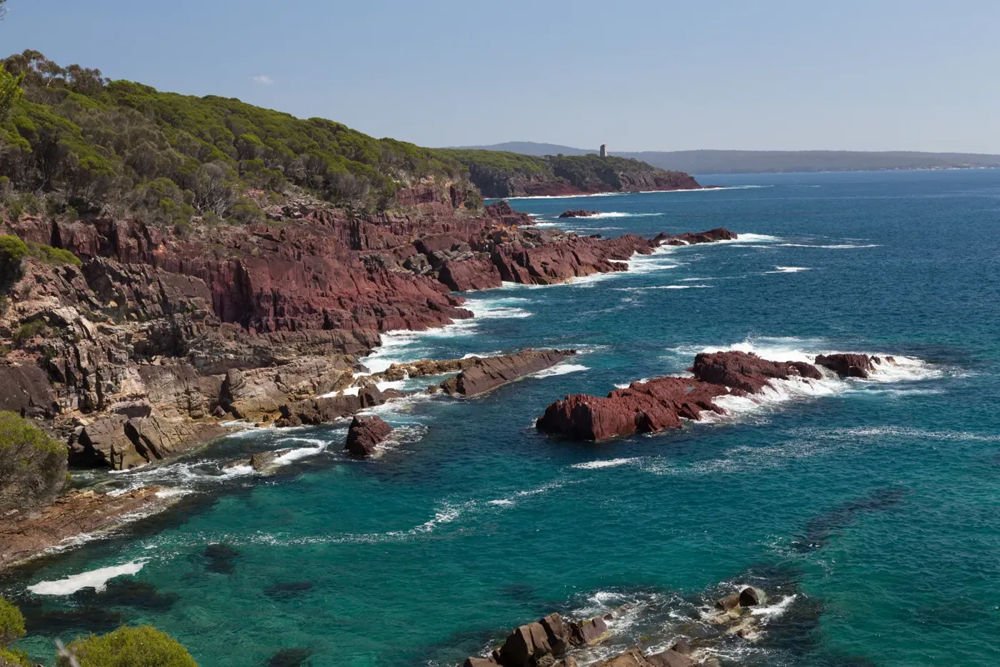 Red rocks and clear water below Boyds Tower in Beowa National Park, near Eden